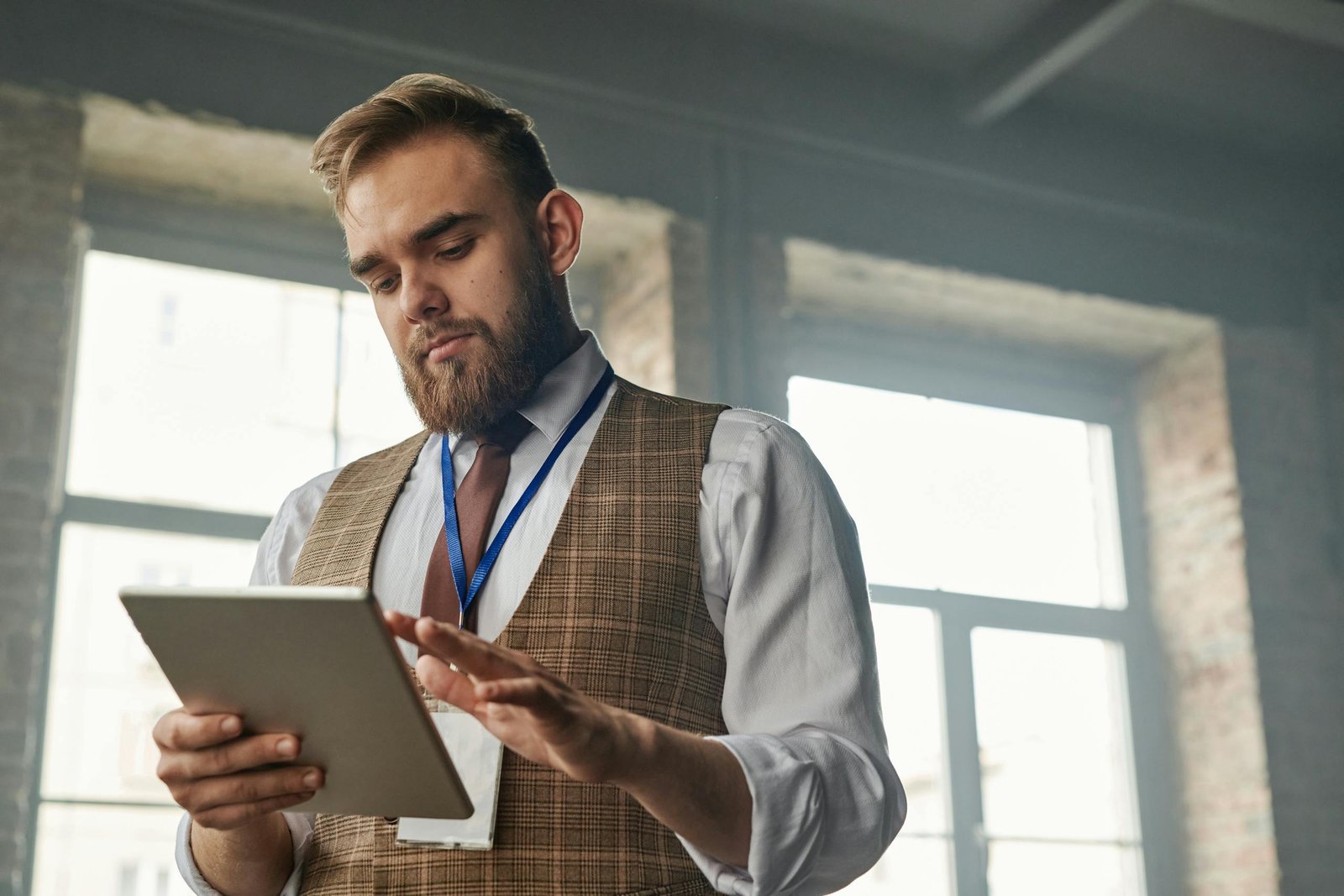 Businessman with a beard uses a tablet computer in a modern office setting, focusing on work.