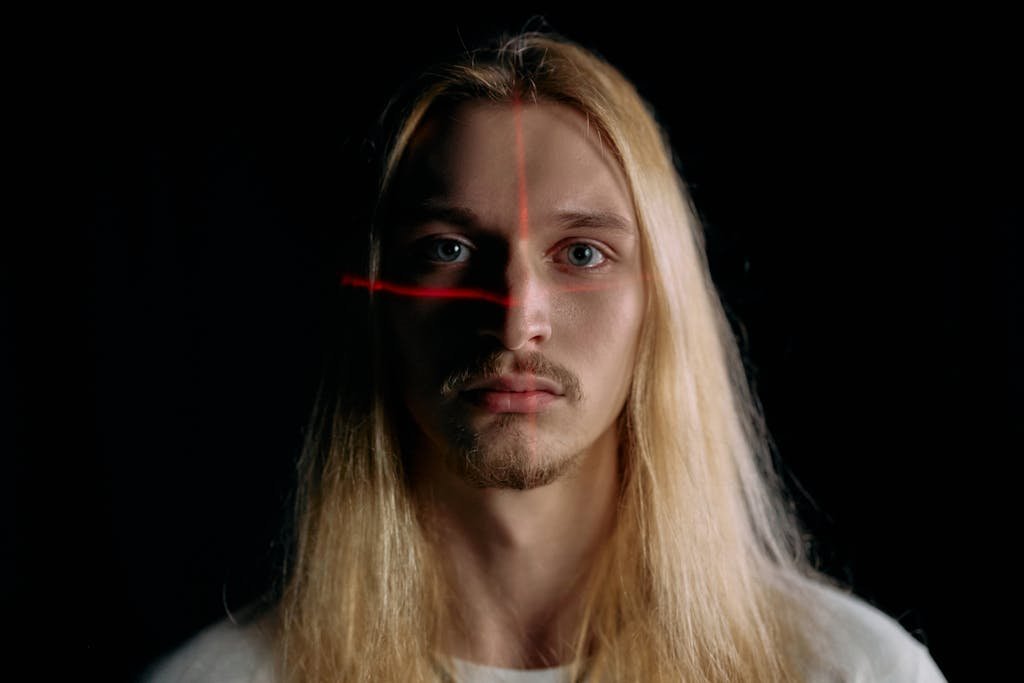 Close-up portrait of a man under laser scanning in low light, showcasing modern facial recognition technology.