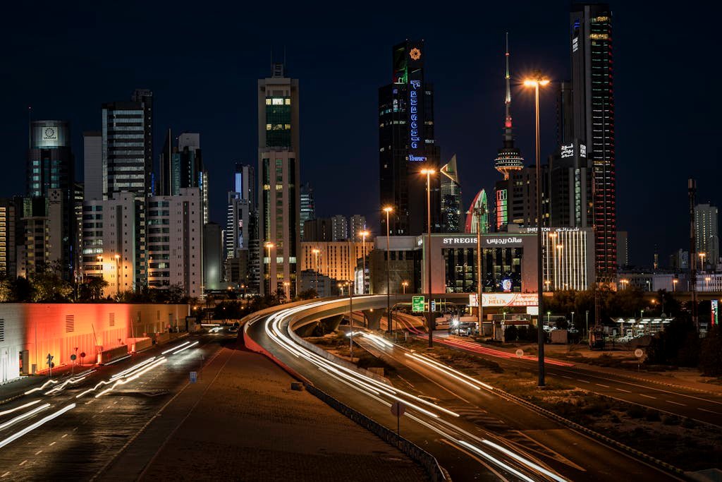 Vibrant night view of Kuwait City's skyline showcasing modern architecture and light trails.
